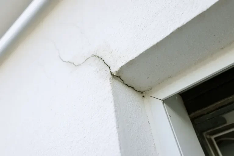 Fissure oblique partant de l’angle d’une fenêtre sur une façade enduite