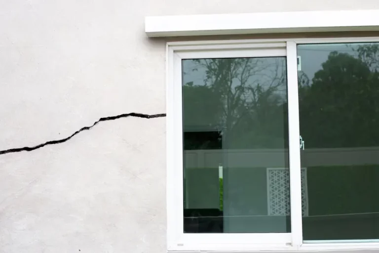 Fissure horizontale sur une façade enduite à côté d’une baie vitrée