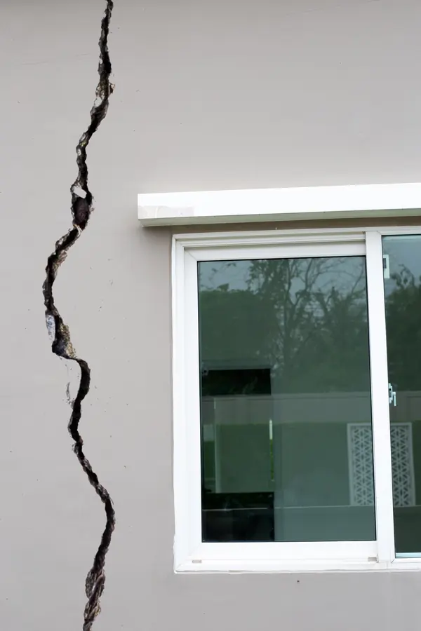 Large fissure traversante sur la façade d’une maison, à faire expertiser